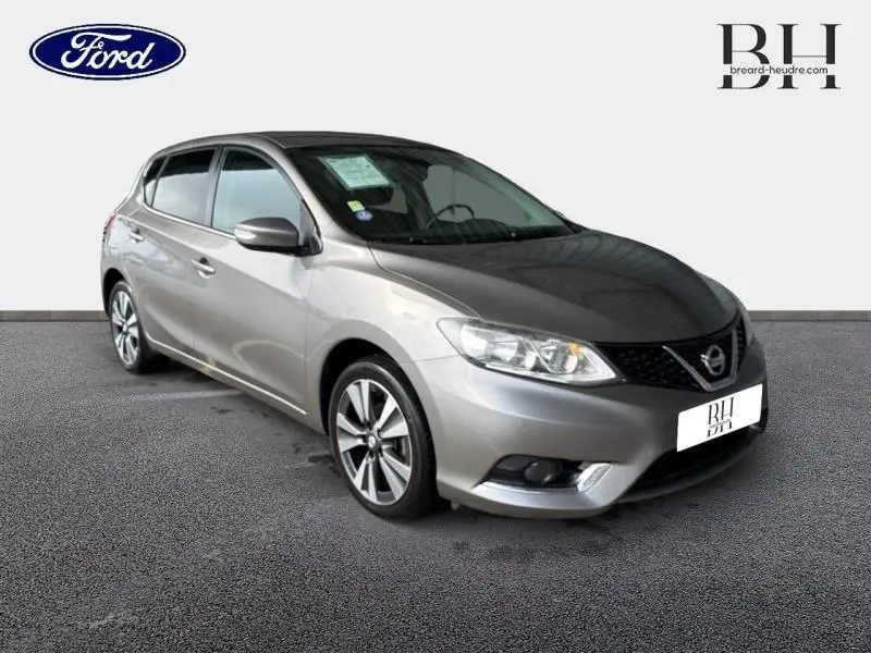 Vue 3/4 avant d'une Nissan Pulsar gris métallisé avec jantes alliage et calandre noire sur fond neutre.