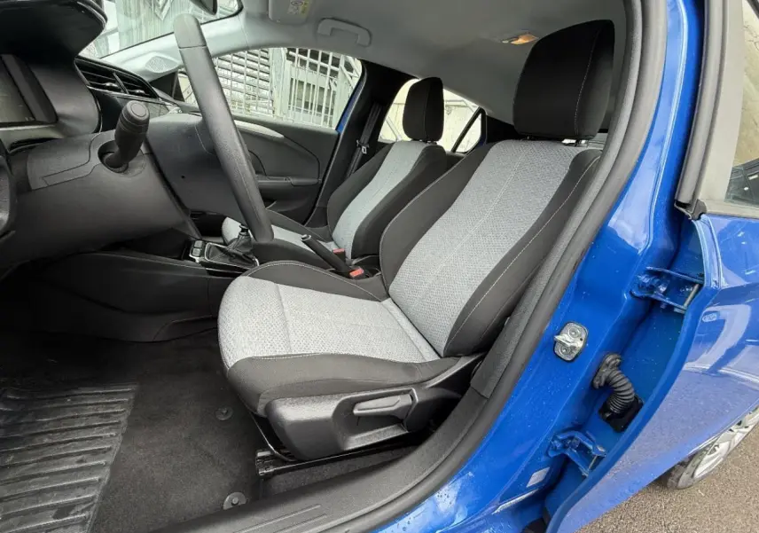 Intérieur de l’Opel Corsa 2025 bleu voltaik, vue côté gauche sur les sièges avant gris et noir avec boîte manuelle.
