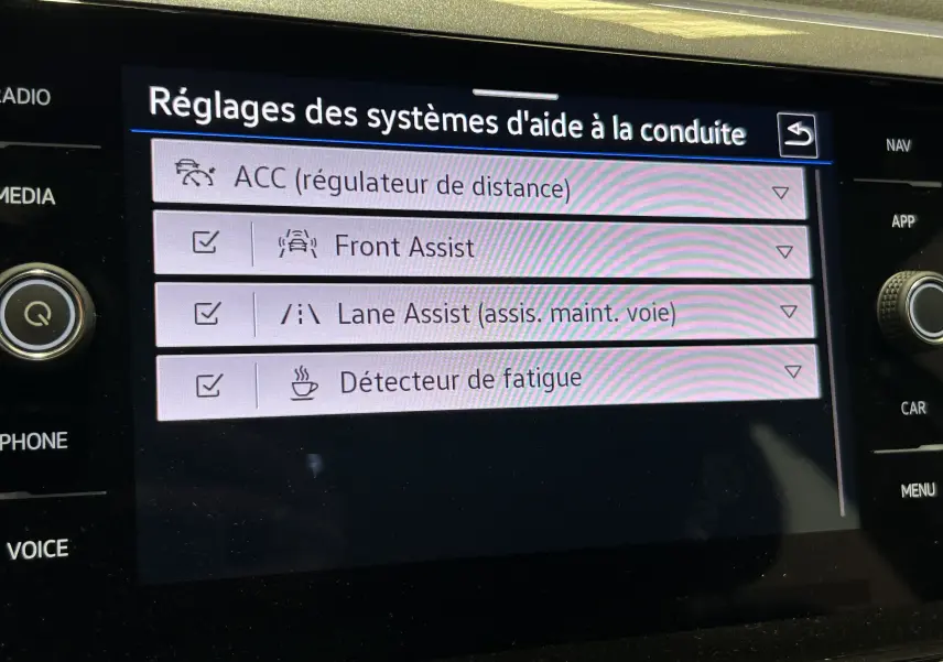 Écran tactile intérieur du Volkswagen Taigo blanc montrant les réglages des aides à la conduite activées.