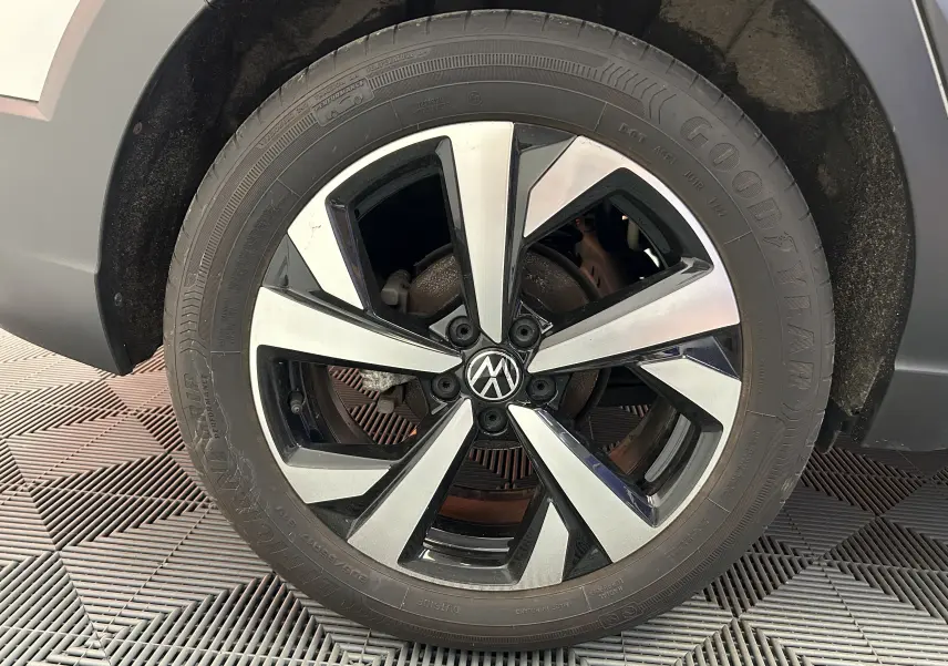 Gros plan sur la roue avant droite du Volkswagen Taigo blanc, mettant en valeur la jante alliage bicolore au design moderne.