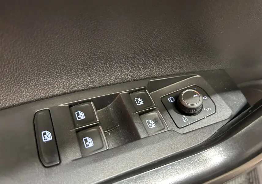 Panneau de commandes des vitres et rétroviseurs électriques sur la portière côté gauche d’un Volkswagen Taigo blanc.