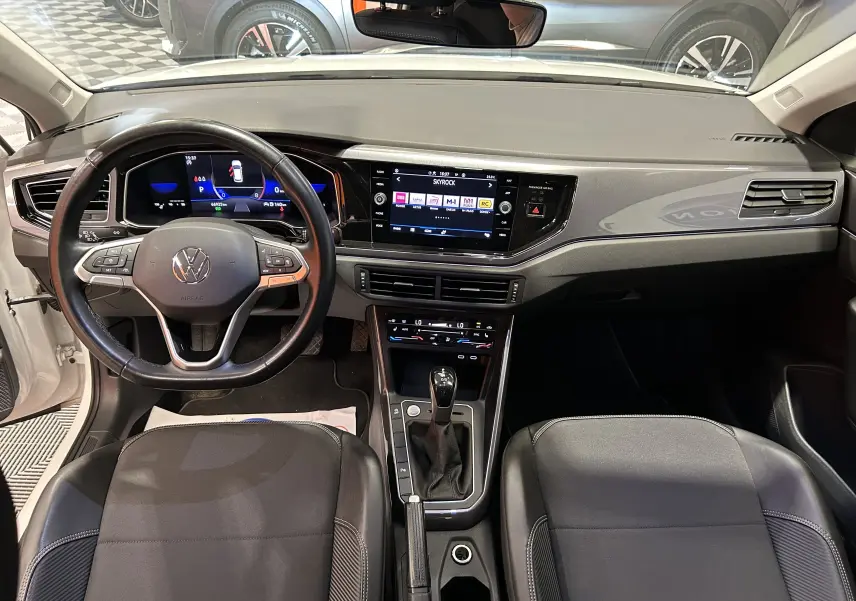 Vue intérieure frontale du tableau de bord et volant noir du Volkswagen Taigo blanc, version TSI 110 DSG7 Style.