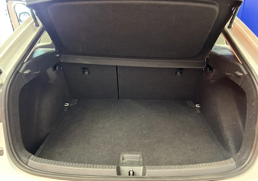 Coffre ouvert vu de l'arrière d'un Volkswagen Taigo blanc pur, espace de chargement vide et tapis noir.