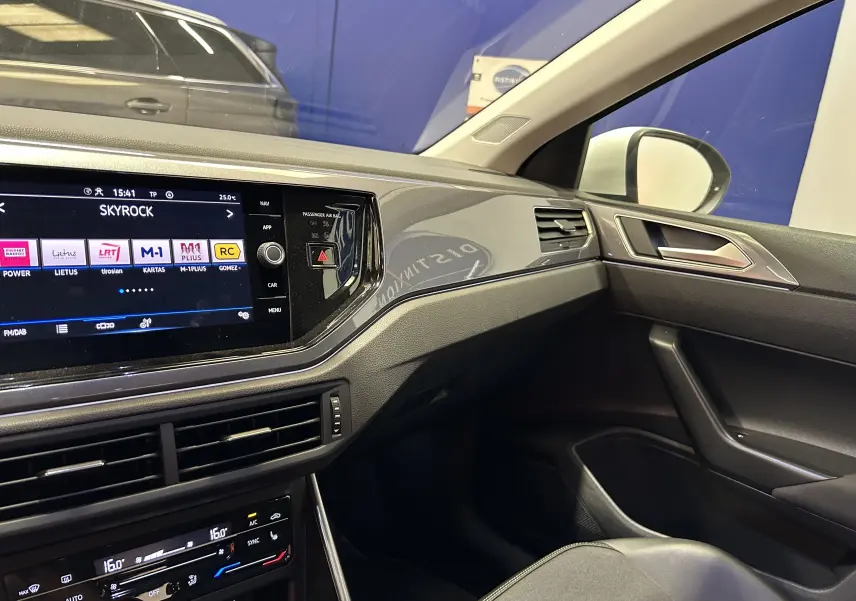 Intérieur côté passager du Volkswagen Taigo blanc, tableau de bord moderne avec écran tactile et commandes climatisation.
