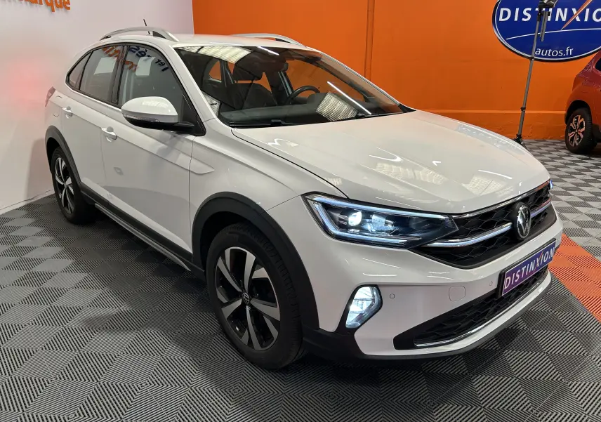 Volkswagen Taigo blanc pur en 3/4 avant droit avec phares LED allumés dans un showroom.