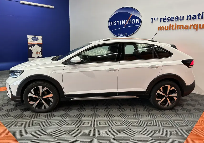 Profil côté gauche d'un Volkswagen Taigo blanc pur 2022 avec jantes alliage et toit panoramique en showroom.