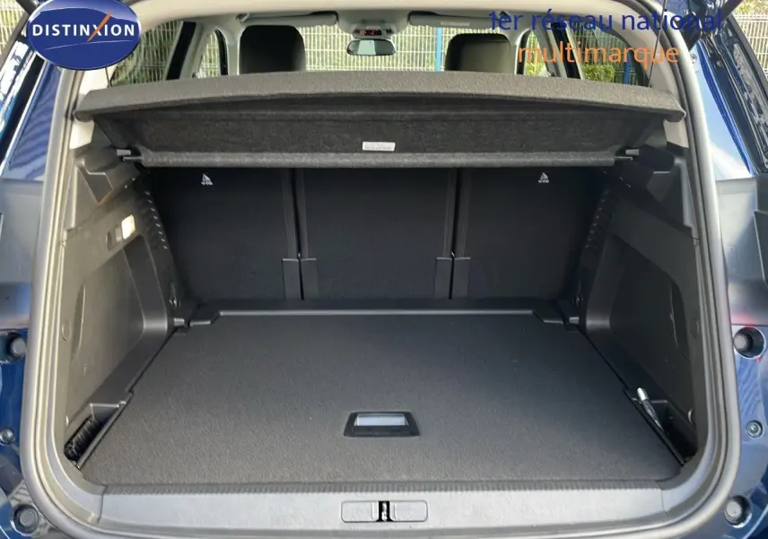 Coffre ouvert vu de l'arrière d'un Citroën C5 Aircross bleu Eclipse Metal, montrant un espace de chargement spacieux et bien fini.