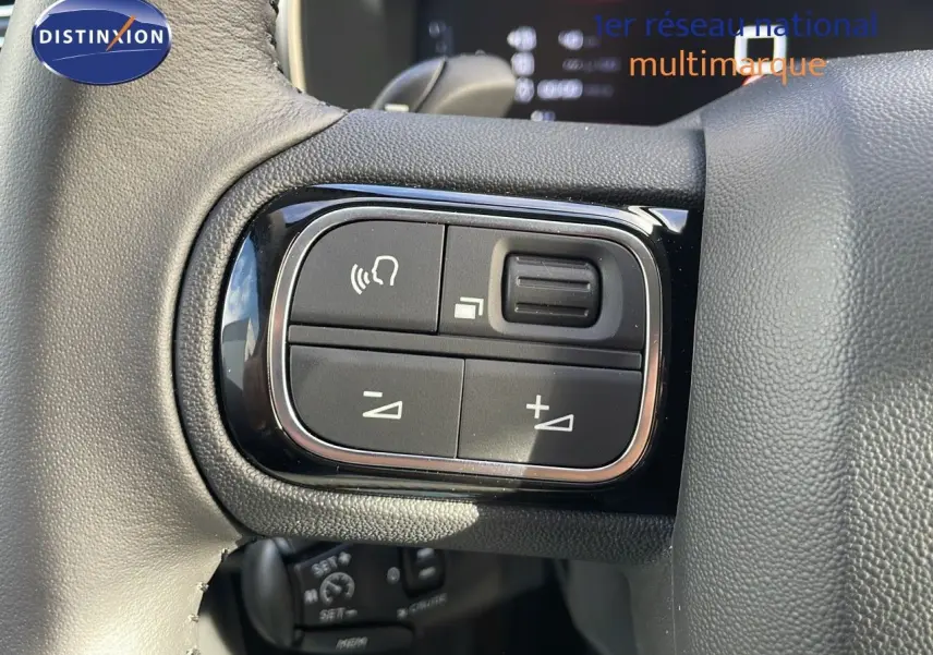 Gros plan sur les commandes du volant du Citroën C5 Aircross 2025 en cuir noir, mettant en valeur les boutons de réglage audio.