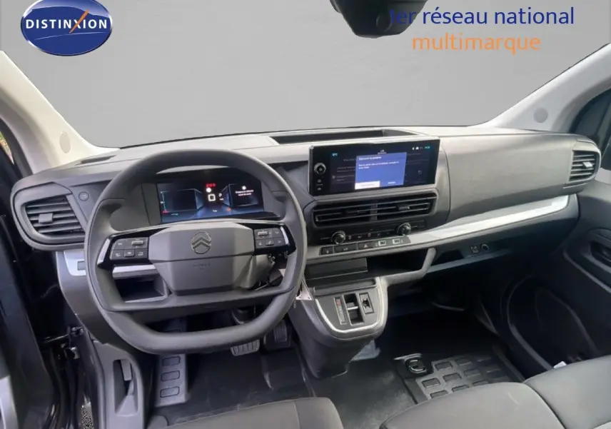Vue intérieure du tableau de bord et volant du Citroën Jumpy gris titane, avec écran tactile central et commandes au volant.