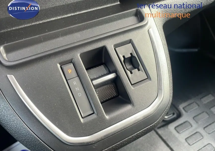 Gros plan sur la console centrale noire du Citroën Jumpy gris titane, avec levier de vitesses automatique et commandes intégrées.