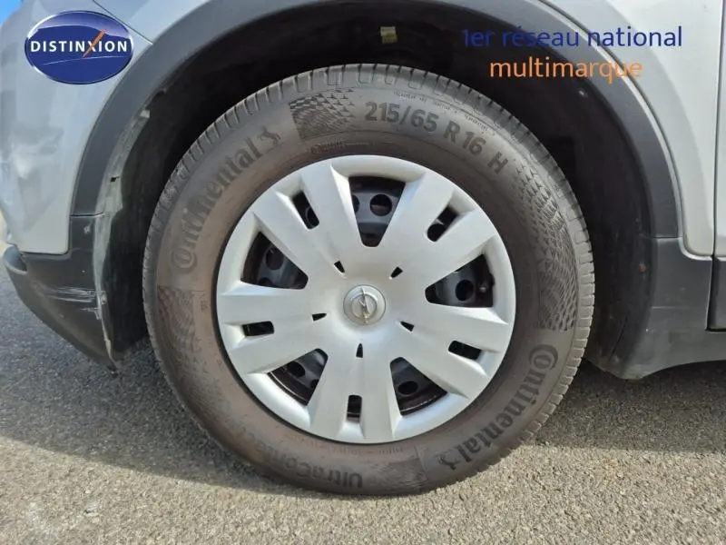 Gros plan sur la roue avant gauche d’un Opel Mokka X gris minéral avec jante en acier et enjoliveur argenté.