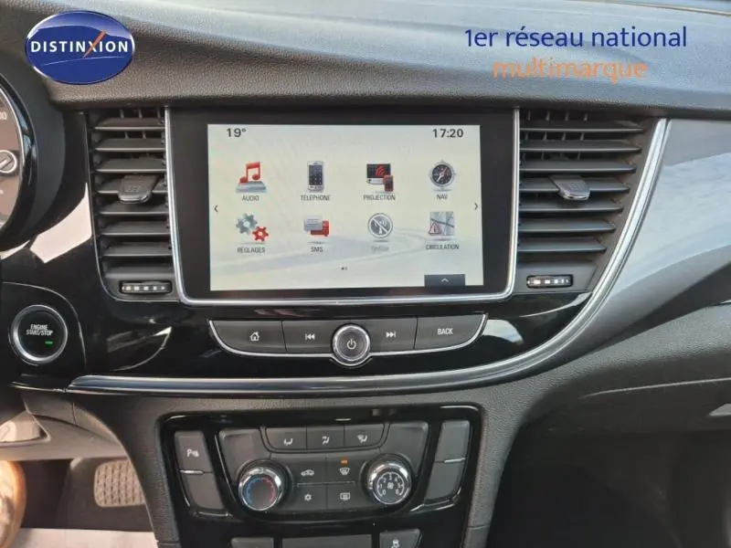 Tableau de bord noir de l’Opel Mokka X 2018 avec écran tactile central et commandes climatisation visibles.