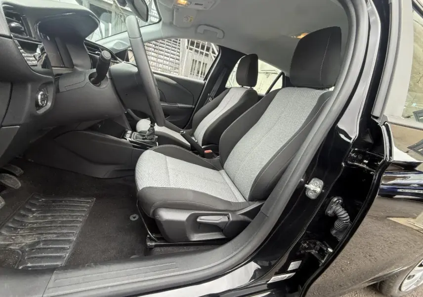 Vue intérieure côté conducteur de l’Opel Corsa 2025 noir karbon, montrant les sièges avant gris et la boîte manuelle.