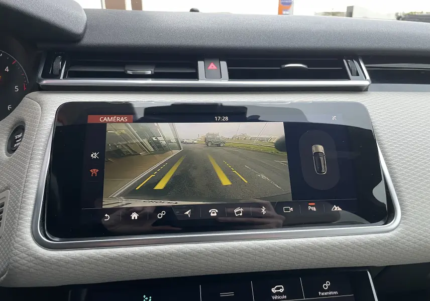 Écran central du Range Rover Velar D300 montrant la caméra de recul avec lignes de guidage jaunes sur route grise.