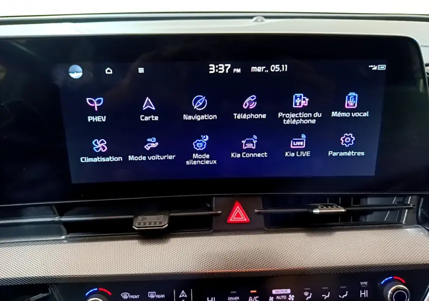 Écran tactile central affichant menu multimédia dans l'habitacle du Kia Sportage blanc, vue intérieure rapprochée.