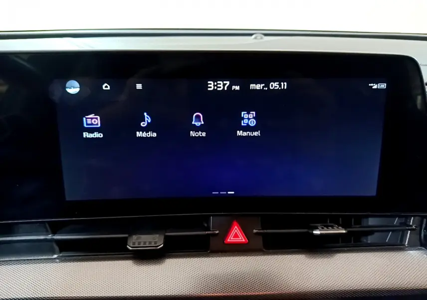 Écran tactile central du tableau de bord du Kia Sportage blanc 2022, affichant les menus Radio, Média, Note et Manuel.