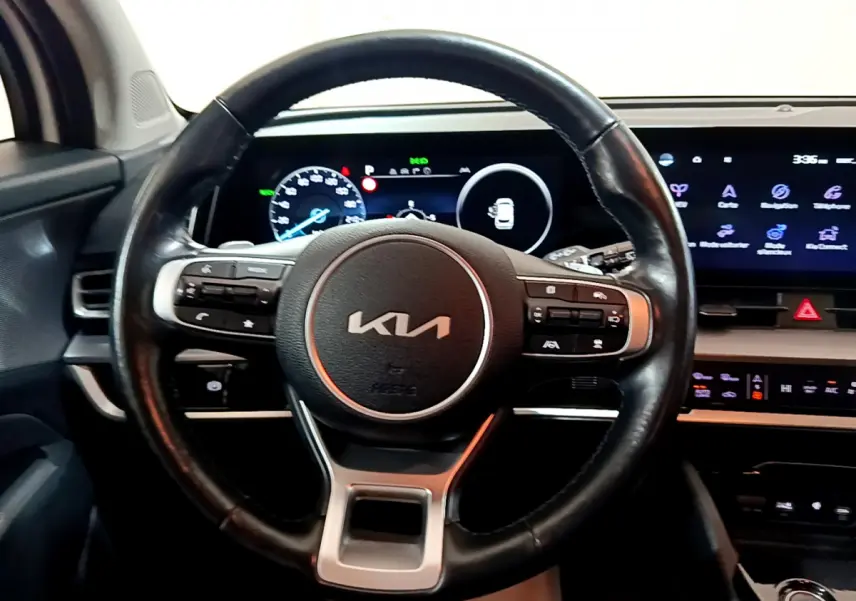 Vue intérieure centrée sur le volant cuir noir du Kia Sportage 2022 avec tableau de bord numérique et écran tactile.