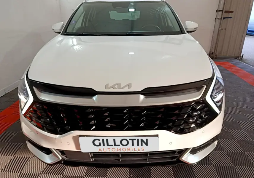 Vue frontale d'un KIA Sportage blanc 2022 avec calandre noire brillante et feux LED en forme de boomerang.
