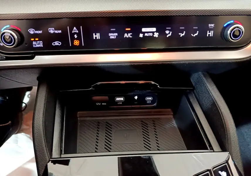 Détail de la console centrale du Kia Sportage blanc 2022 montrant la commande de climatisation digitale et la zone de recharge sans fil.
