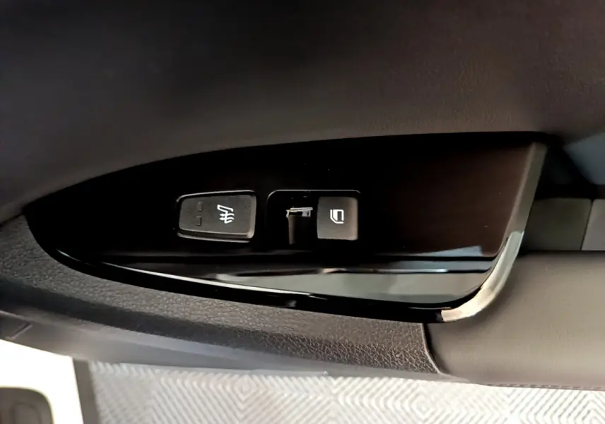 Boutons de réglage des rétroviseurs côté conducteur sur panneau noir brillant dans un KIA Sportage blanc 2022.