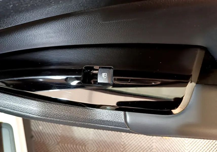 Gros plan sur le bouton de commande de lève-vitre électrique côté gauche dans l'habitacle du KIA SPORTAGE blanc 2022.