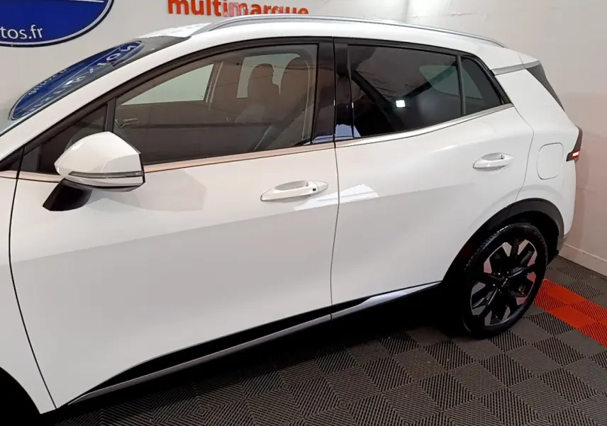 Vue latérale côté gauche du KIA SPORTAGE blanc 2022 avec jantes noires et rétroviseurs intégrant clignotants.