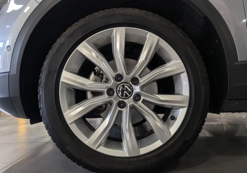 Gros plan sur la roue avant gauche du Volkswagen T-Roc gris pyrite 2024 avec jante alliage 18 pouces à 10 branches.