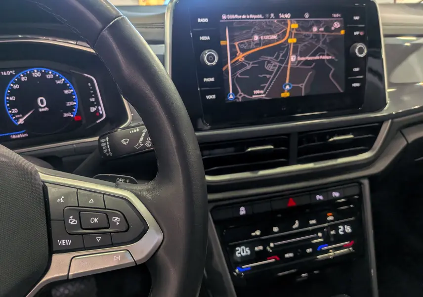 Vue rapprochée de l'intérieur du Volkswagen T-Roc 2024, tableau de bord avec écran tactile et volant en cuir noir.