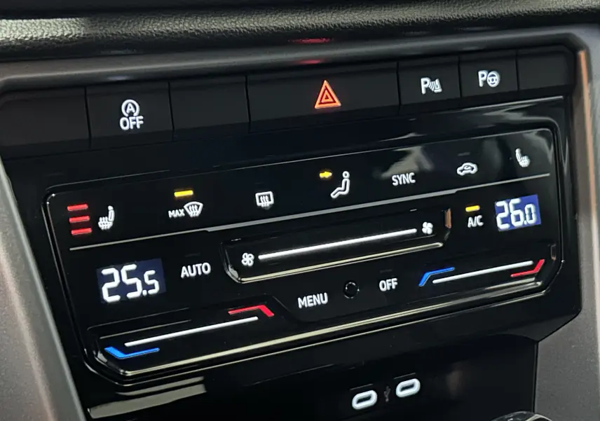 Gros plan sur la console centrale du Volkswagen T-Roc 2025, affichant la climatisation bi-zone et les sièges chauffants.