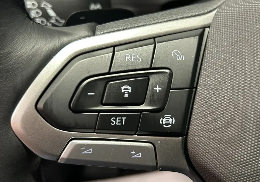 Gros plan sur les commandes de régulateur de vitesse au volant du Volkswagen T-Roc 2025 gris Indium Metal.