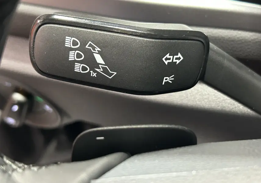 Gros plan sur la manette de clignotants et feux du Volkswagen T-Roc 2025, intérieur noir.