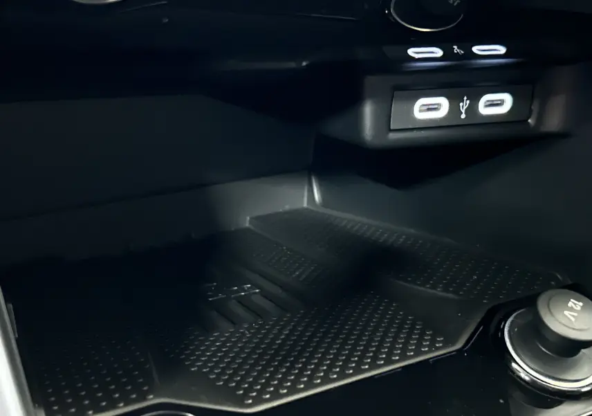 Gros plan sur le compartiment de recharge avec ports USB et prise 12V dans un Volkswagen T-Roc 2025 gris Indium.