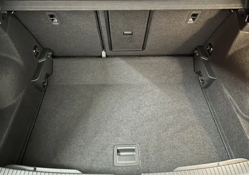 Coffre spacieux du Volkswagen T-Roc TSI 150 DSG Life 30 Years, vue intérieure avec revêtement gris foncé et fixations visibles.