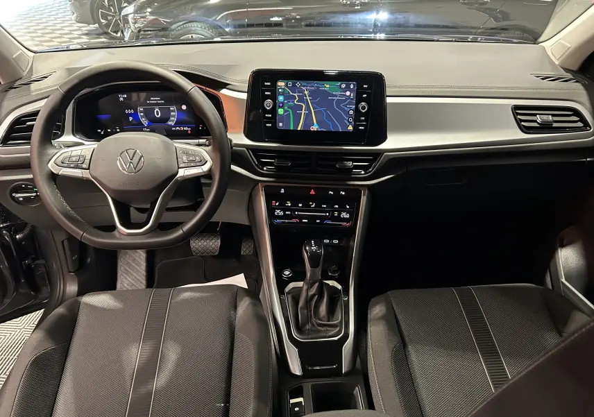 Vue intérieure du tableau de bord du Volkswagen T-Roc 2025, avec écran tactile central affichant la navigation.