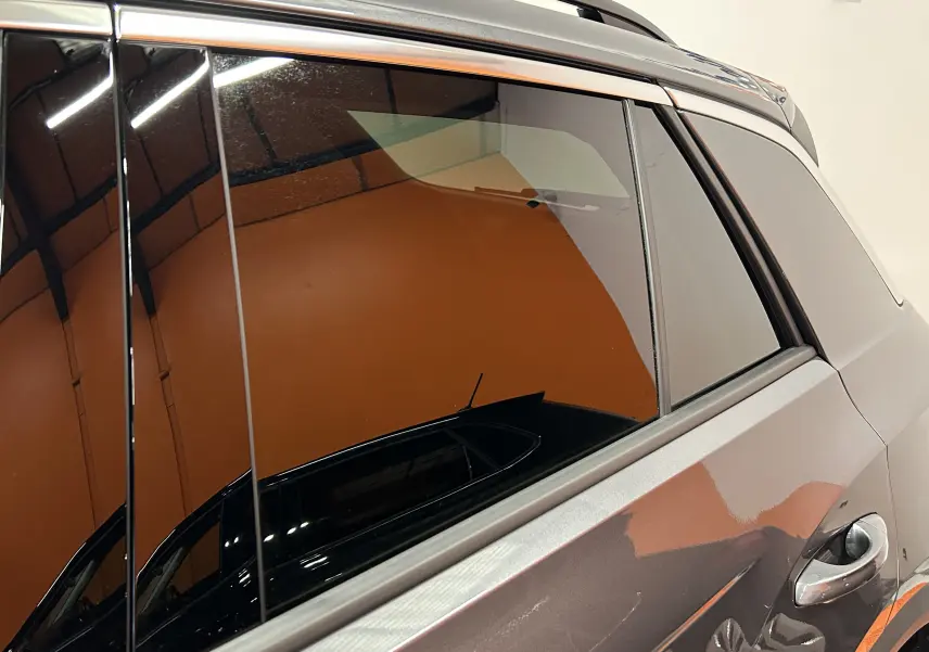 Gros plan sur la porte arrière droite gris Indium métal du Volkswagen T-Roc 2025 avec vitre teintée et poignée chromée.