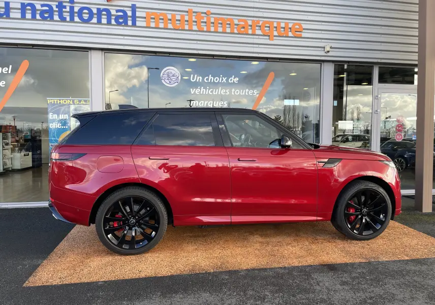 Vue de profil côté gauche d’un Range Rover Sport P440 HSE R-Dynamic rouge Italian Racing avec jantes noires 23 pouces et toit noir.