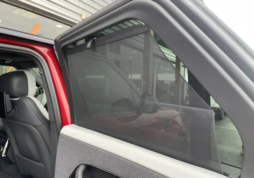 Vue intérieure côté gauche arrière du Range Rover Sport P440 HSE R-Dynamic rouge Italian Racing avec pare-soleil en filet déployé.