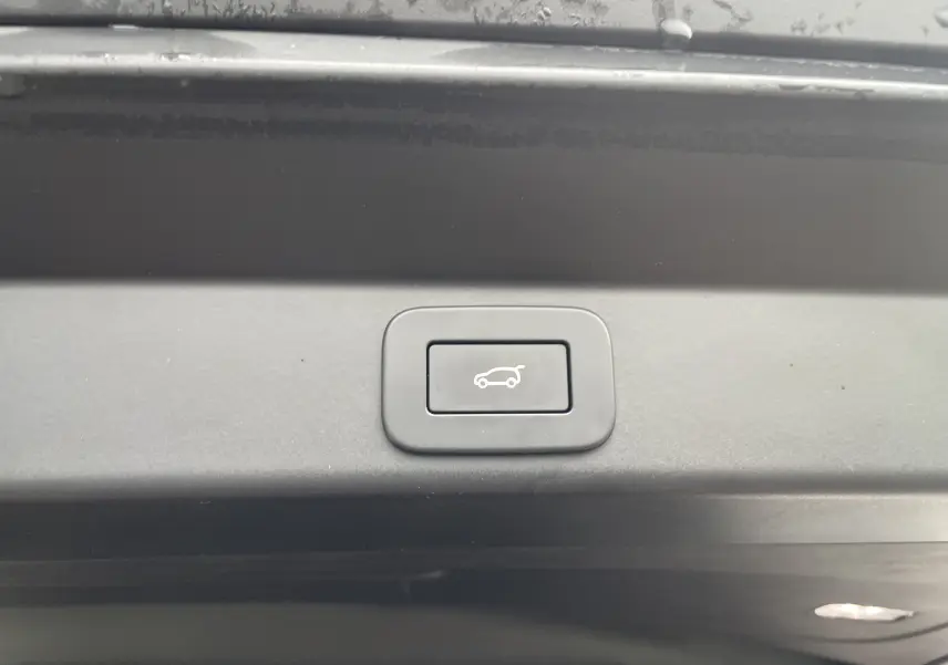 Gros plan sur le bouton d'ouverture électrique du coffre, intérieur noir du Range Rover Sport P440 HSE R-Dynamic 2023.