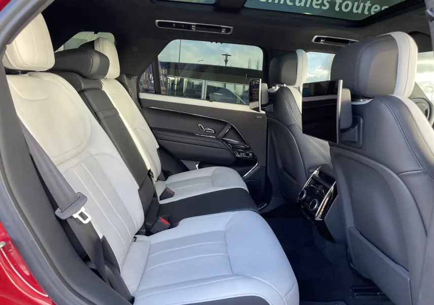 Vue intérieure arrière côté gauche du Range Rover Sport P440 HSE R-Dynamic 2023, sièges cuir blanc avec écrans intégrés aux appuie-têtes.