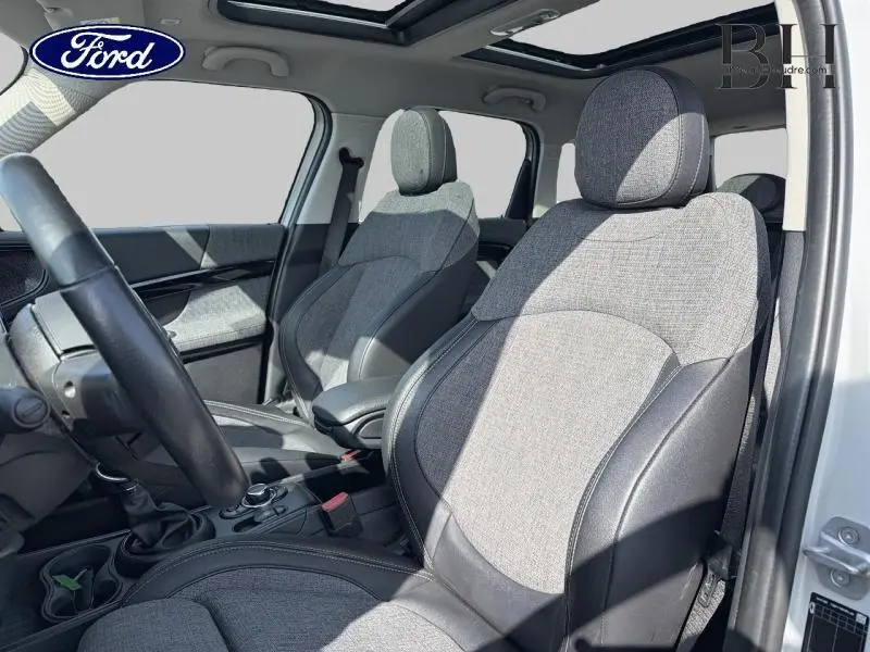 Vue intérieure côté conducteur du MINI Countryman Cooper SE 2021, sièges tissu gris et cuir noir, toit panoramique ouvert.