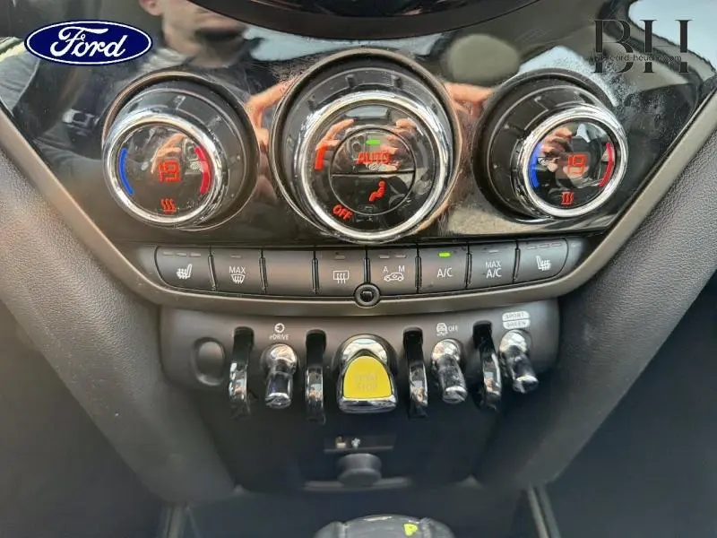 Vue rapprochée du tableau de bord de la MINI Countryman Cooper SE en Moonwalk Grey, avec commandes de climatisation et boutons chromés.