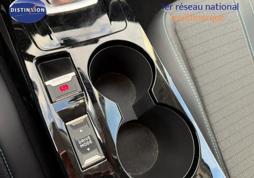 Gros plan sur la console centrale noire brillante du Peugeot 2008 1.2 PureTech, avec boutons frein à main et mode de conduite.