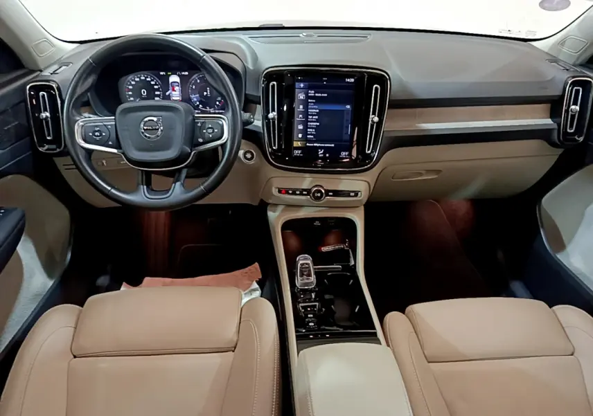 Intérieur du Volvo XC40 T3 2020 vu de face, tableau de bord beige avec écran tactile central et volant cuir noir.