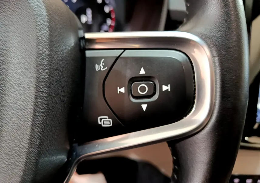 Gros plan sur les commandes du volant cuir noir du Volvo XC40 T3 Inscription 2020, avec boutons multifonctions et cadre alu.