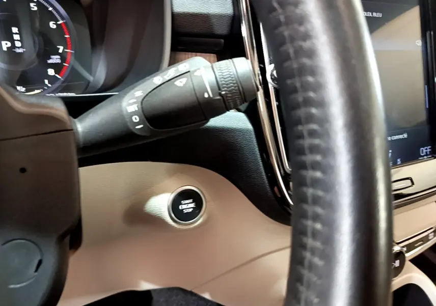 Gros plan sur le bouton démarrage et partie du volant en cuir noir du tableau de bord beige d'un Volvo XC40 T3 2020.