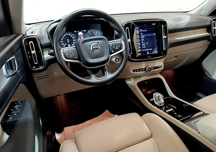 Vue intérieure du tableau de bord beige et noir du Volvo XC40 T3 2020, avec volant cuir et écran tactile central.