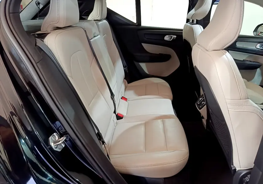 Vue intérieure côté gauche des sièges arrière en cuir beige du Volvo XC40 T3 noir, mettant en valeur l'espace et les finitions.