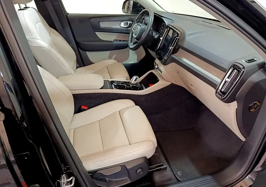Vue intérieure côté conducteur du Volvo XC40 T3 2020 noir, sièges cuir beige et tableau de bord moderne avec écran tactile vertical.