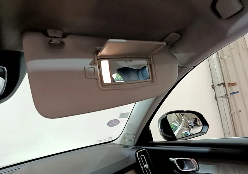 Détail du pare-soleil côté conducteur avec miroir éclairé dans l'habitacle noir du Volvo XC40 T3 2020.