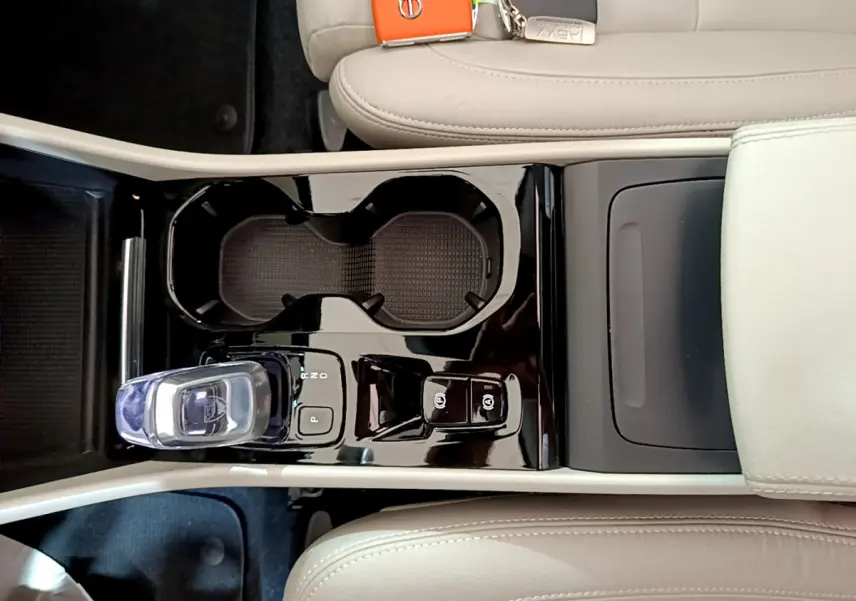 Vue plongeante sur la console centrale noire brillante du Volvo XC40 T3 2020 avec levier de vitesse cristal et sièges beige clair.